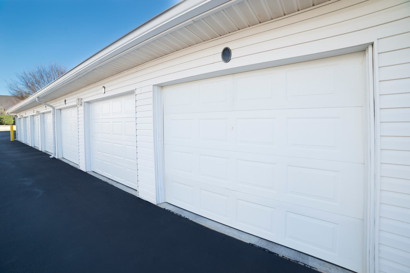 A row of white garage doors along a multi-unit building