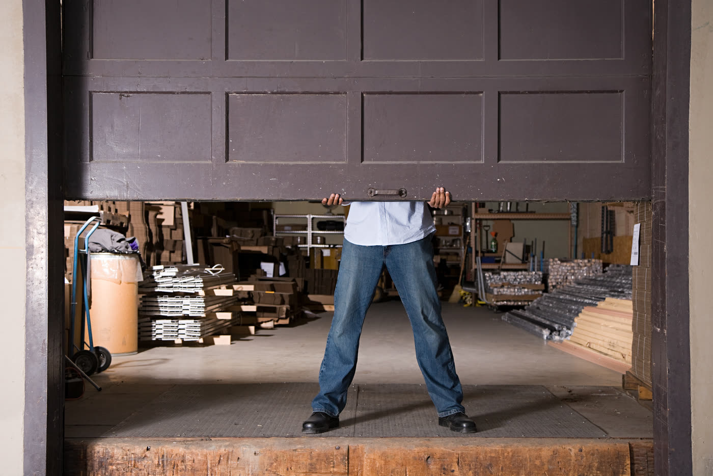 Someone holding a garage door up by hand because it will not run on its track