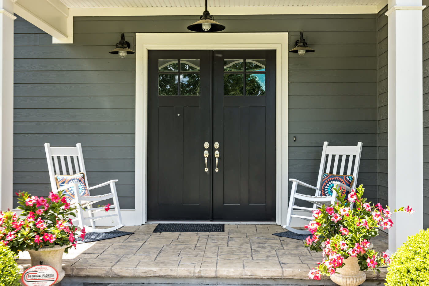 A pair of dark craftsman entry doors on a covered porch