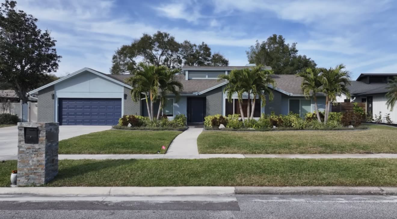 The full front elevation of the repainted house with matching navy entry and garage doors