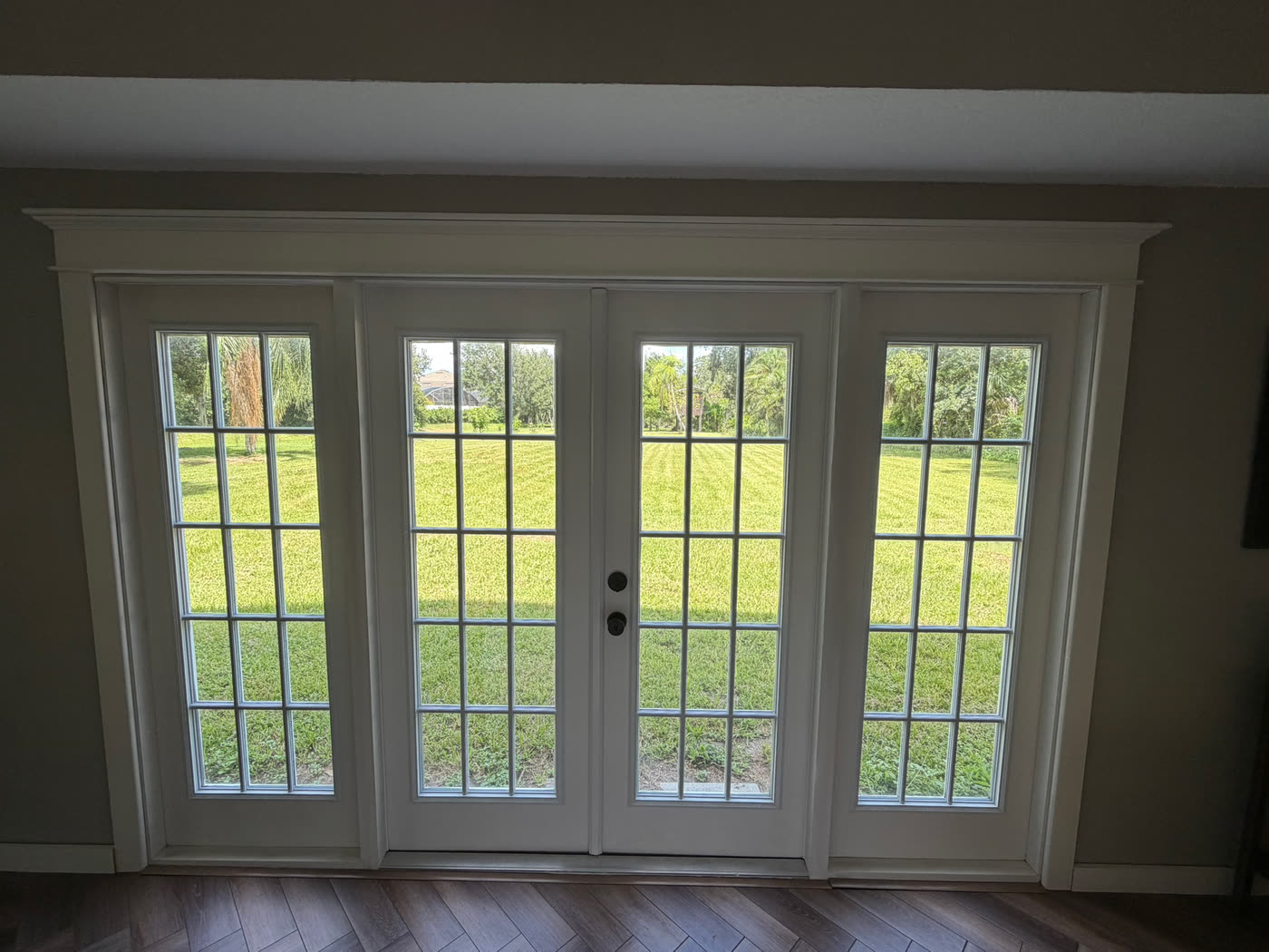 The finished French doors with matching sidelights, new casing and a wood floor