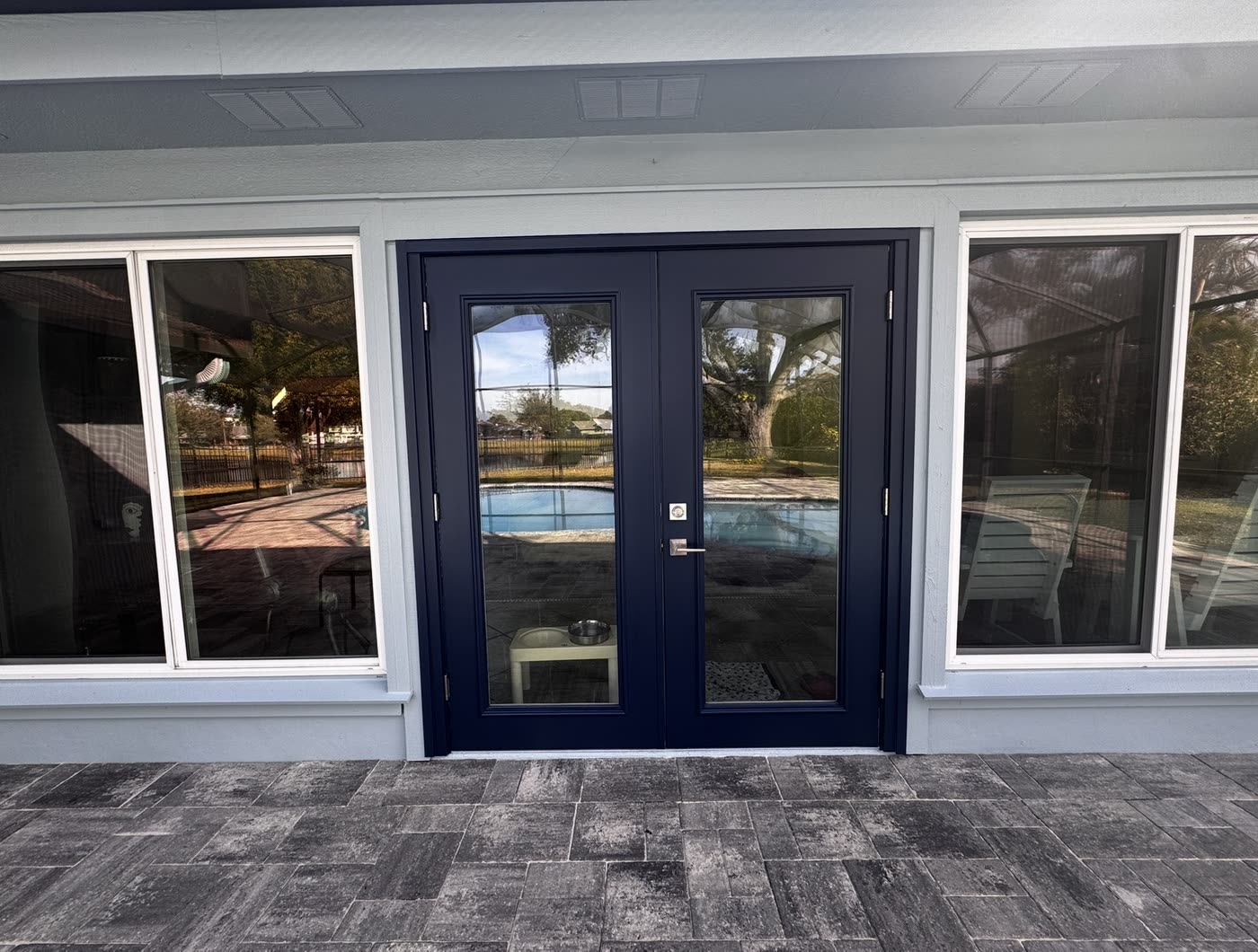 Navy double patio doors in a repainted wall above a new paver deck