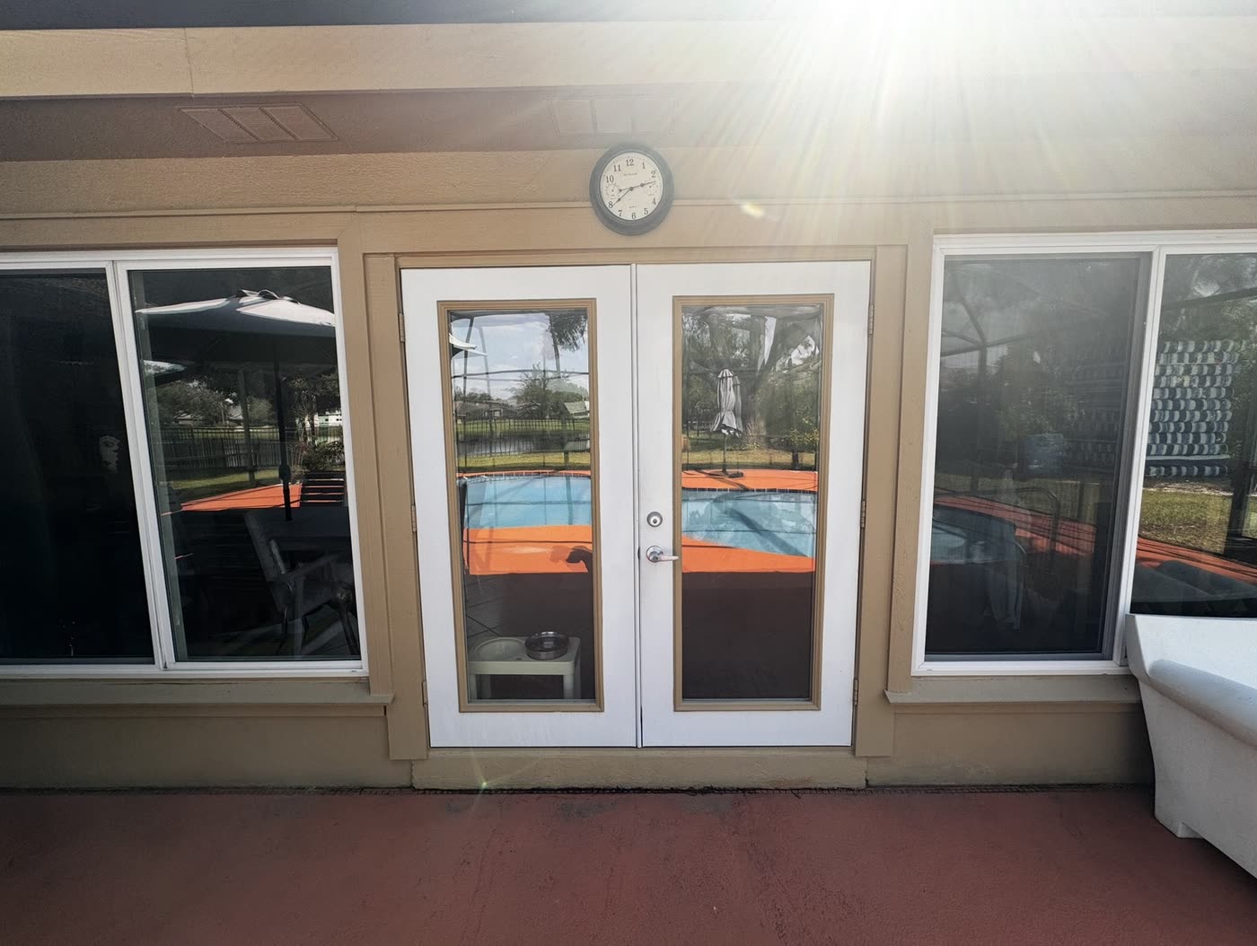 The original white patio doors in a tan wall above a painted concrete deck