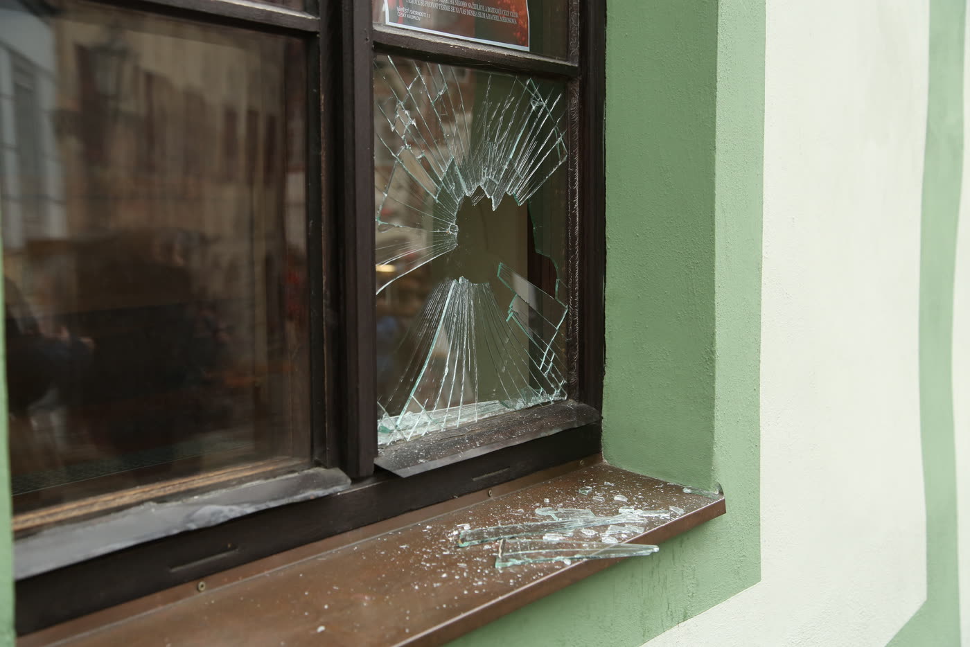 A window pane broken through, with glass fragments on the sill