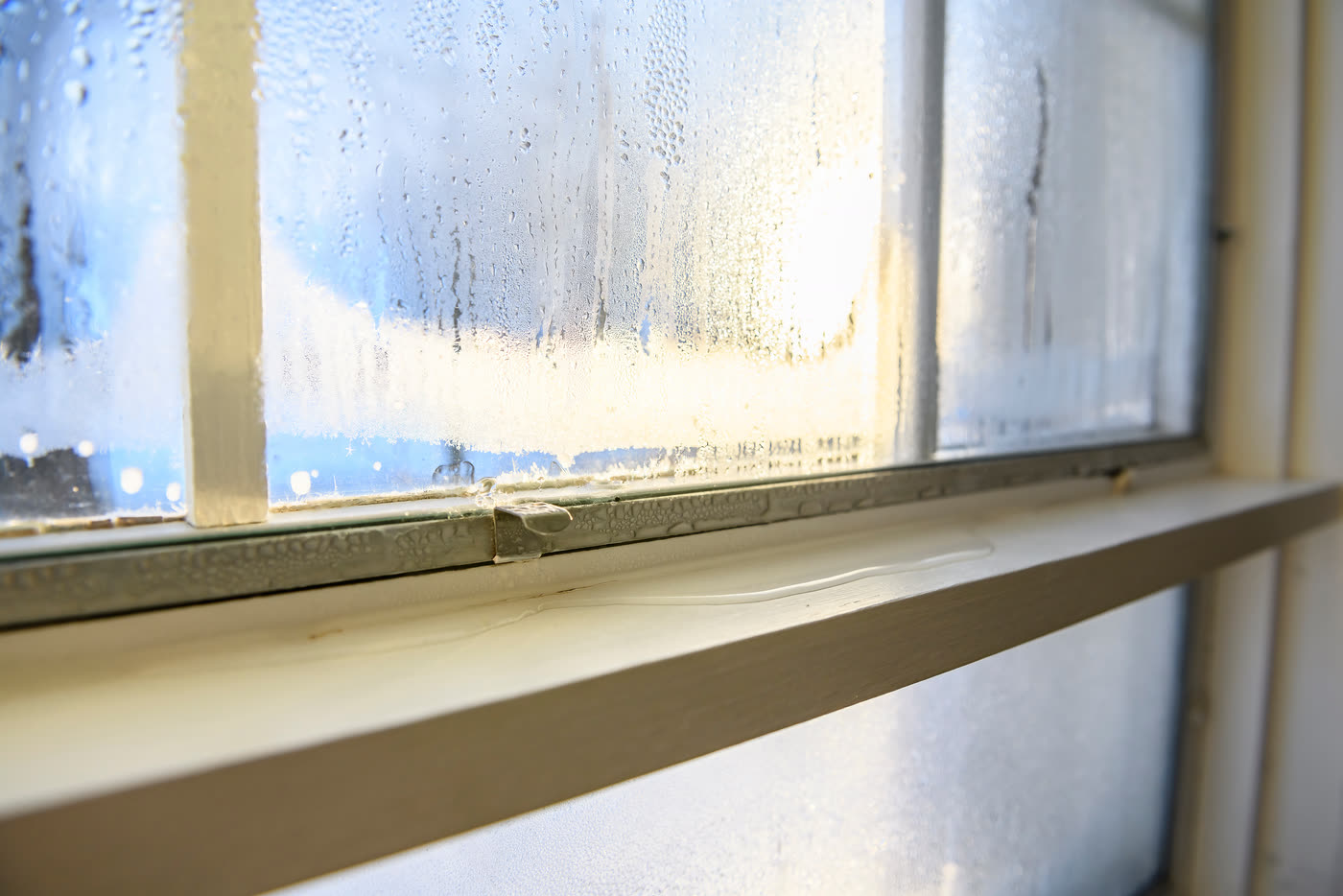 Water pooling on a window sill beneath a fogged pane